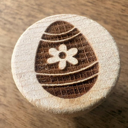 Wooden stamp with an Easter egg design on a wooden surface